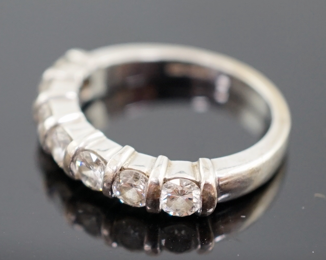 A modern 18ct white gold and seven stone round brilliant cut diamond set half hoop ring